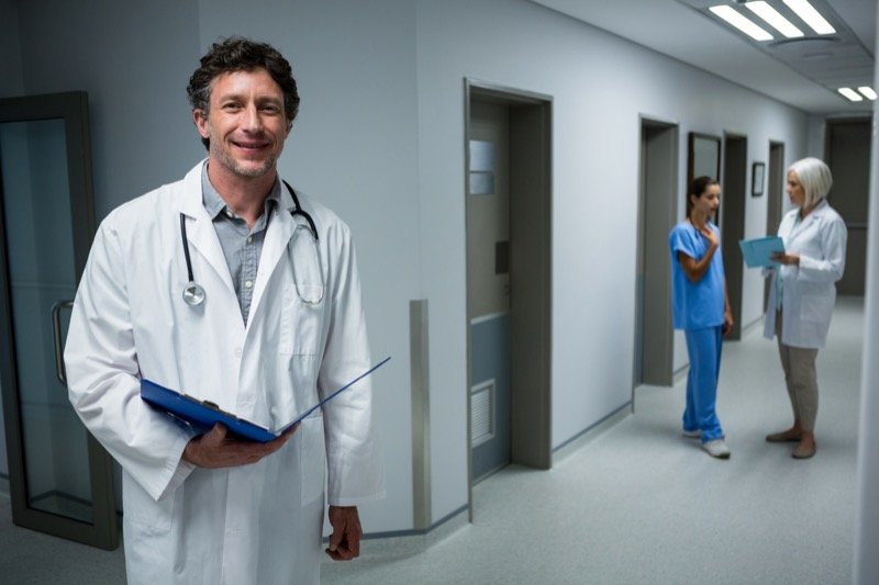 Doctor holding medical report in hospital corridor